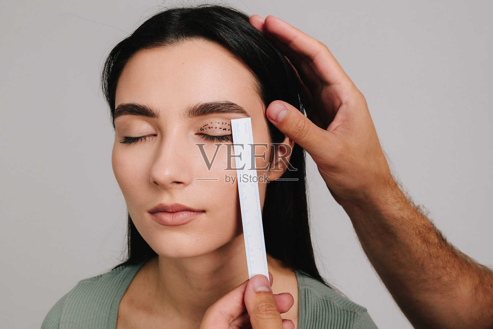 眼睑成形术。整形外科医生正在为患者测量眼部手术距离。准备进行眼睑成形术以矫正下垂的眼睑。上眼睑成形术。照片摄影图片