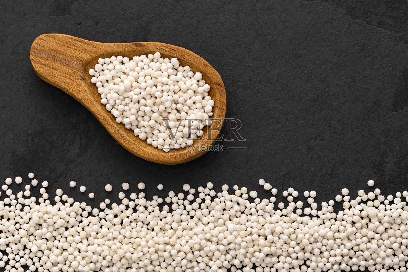 木薯根制成的西米珍珠 - 勺子上的白色西米球。木薯。照片摄影图片