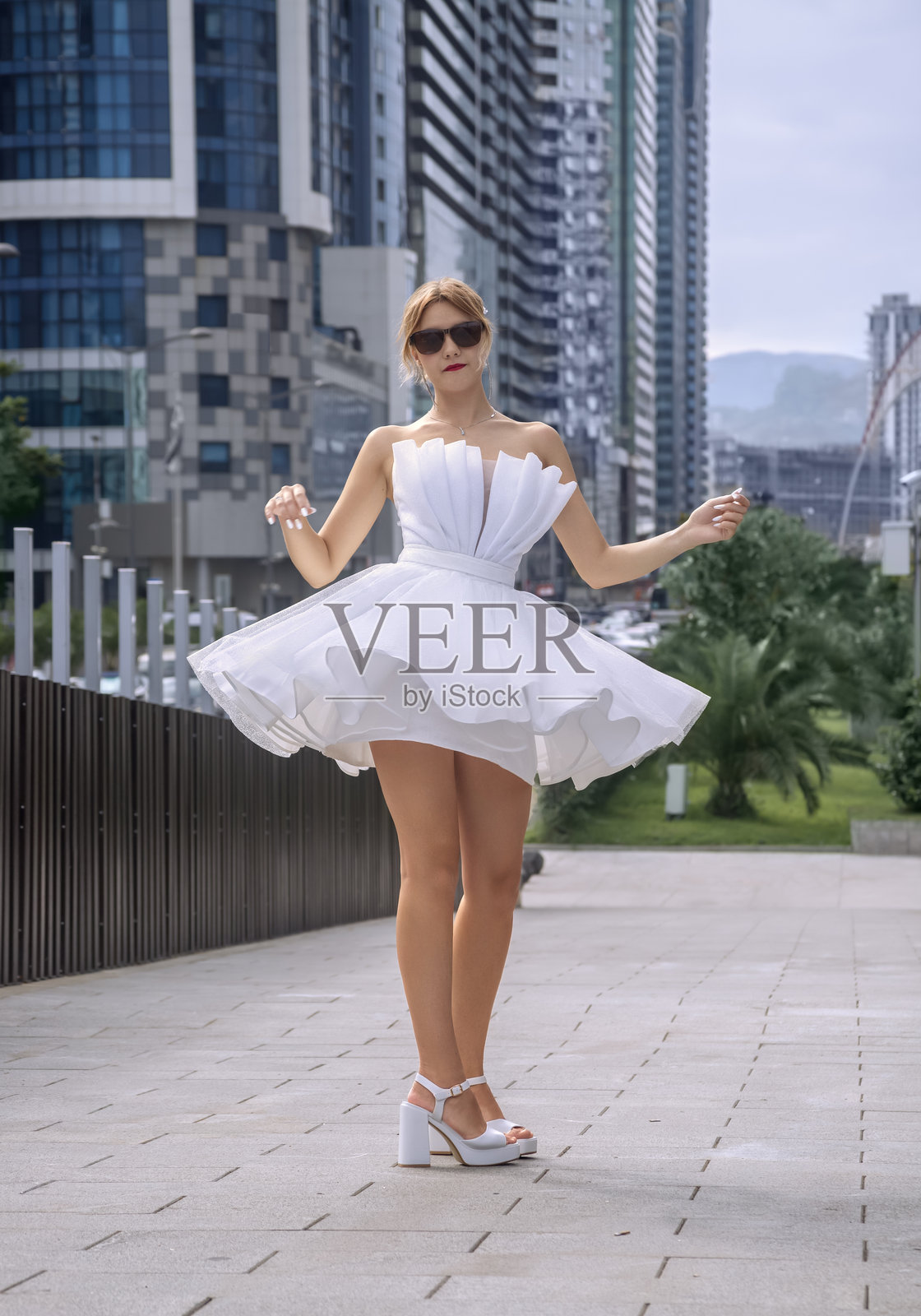 以玻璃建筑为背景，新娘在桥上旋转。全身照照片摄影图片