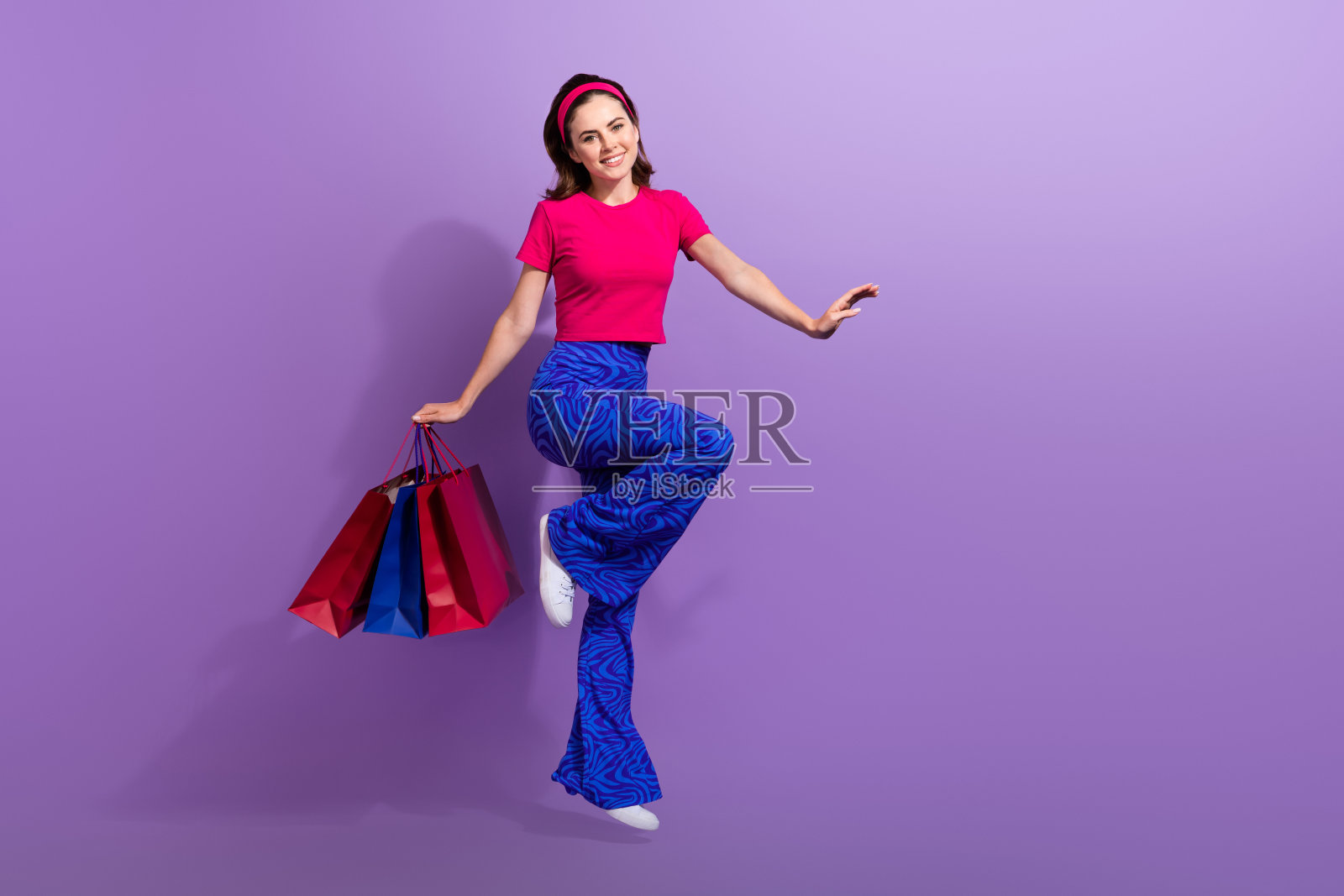 全身照，迷人的漂亮女士在商场购买时尚优质服装，背景为紫色，空旷空间。照片摄影图片
