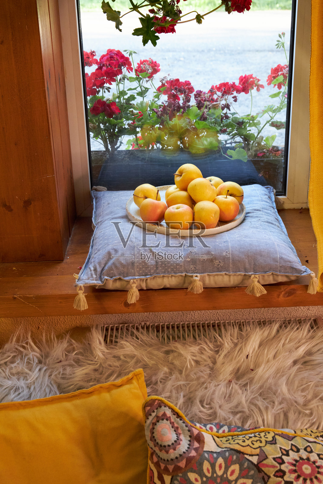 窗台上的静物，蓝色垫子上放着一个装有黄色苹果的陶瓷盘。照片摄影图片