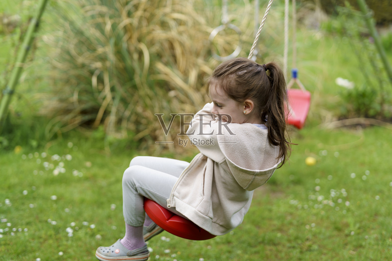小女孩在夏天的后院秋千上玩得很开心。快乐的童年概念照片摄影图片