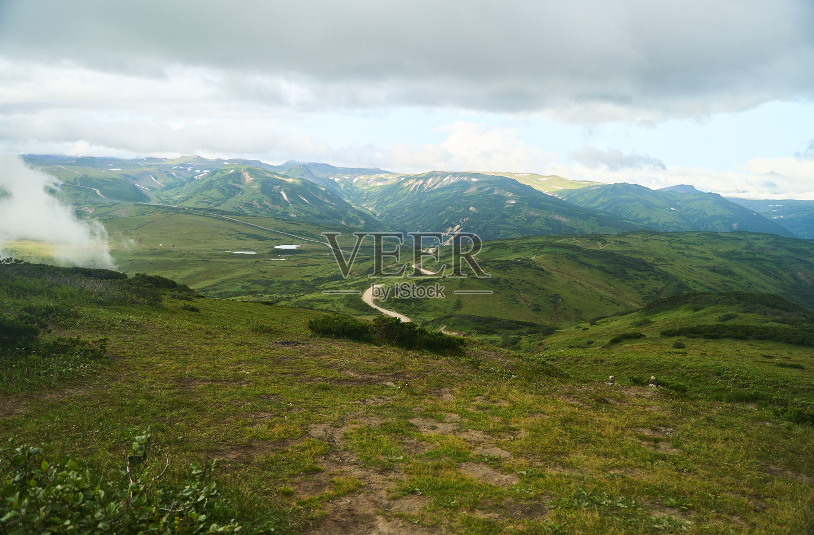 堪察加地区。令人惊叹的山脉景观展现了美丽的绿色山丘，点缀着蓬松的云朵。照片摄影图片