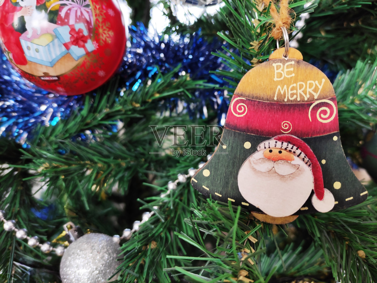 装饰性圣诞树玩具，形状为铃铛，上面有戴红色帽子的圣诞老人面孔照片摄影图片