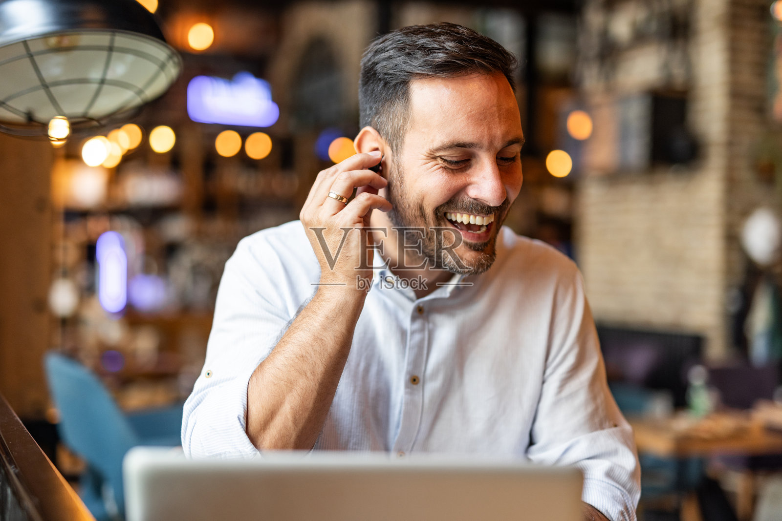满意的现代商人穿着时髦的衣服坐在咖啡馆用智能手机和耳机照片摄影图片