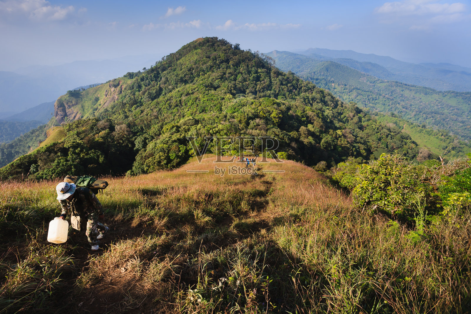 旅行者沿着山脊上的小路行走。照片摄影图片