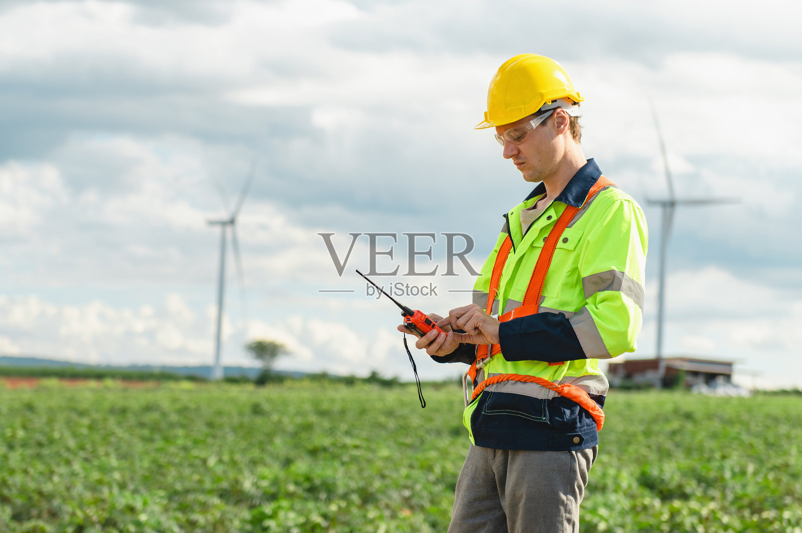 身穿黄橙相间安全背心的男子正在看一个装置照片摄影图片