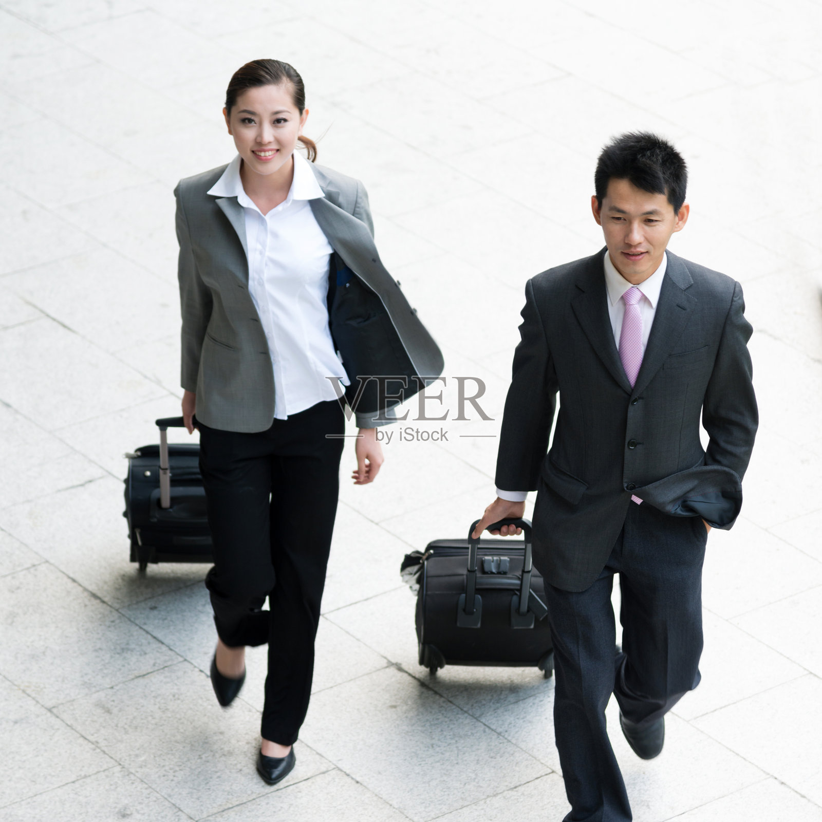 商务男士和商务女性拉着拉杆箱在大厅照片摄影图片