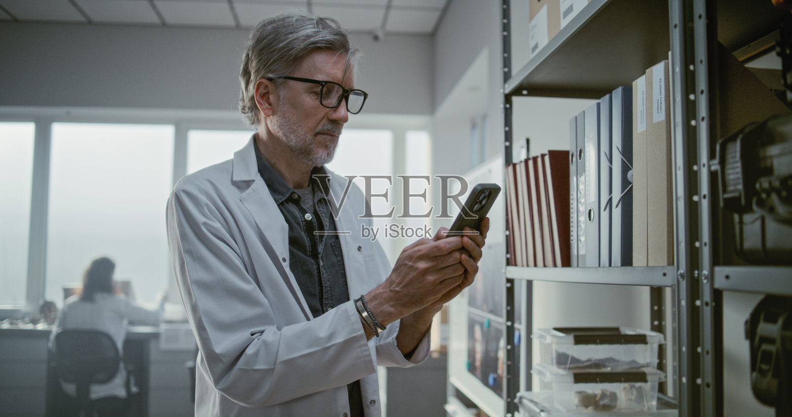 考古实验室：成熟的科学家正在用手机聊天或上网照片摄影图片