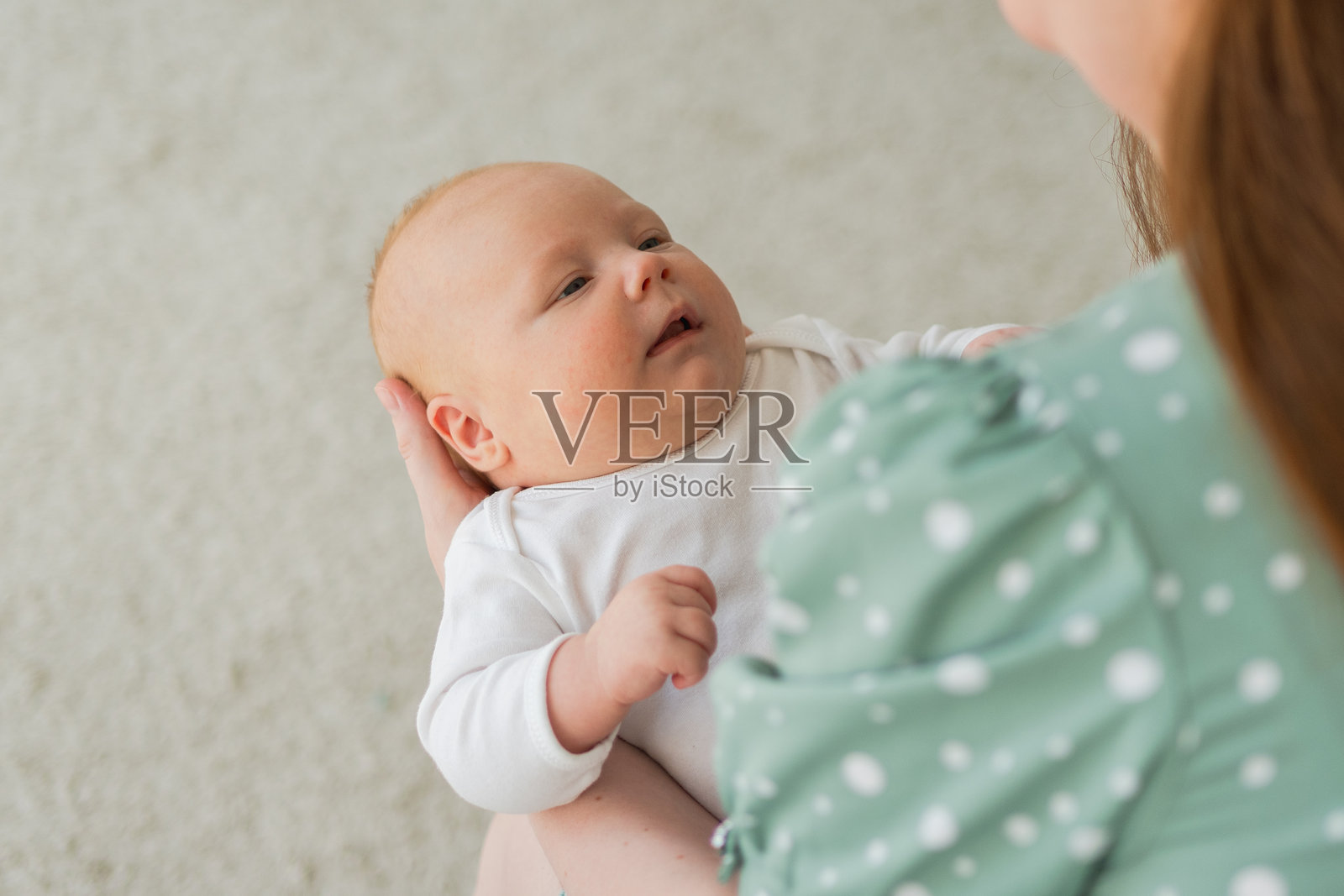 快乐的家庭在家中。母亲抱着小女儿。妈妈和小女孩在家中放松、玩耍，享受快乐时光。母亲充满爱意地拥抱着宝宝。妈妈正在给宝宝哺乳。照片摄影图片