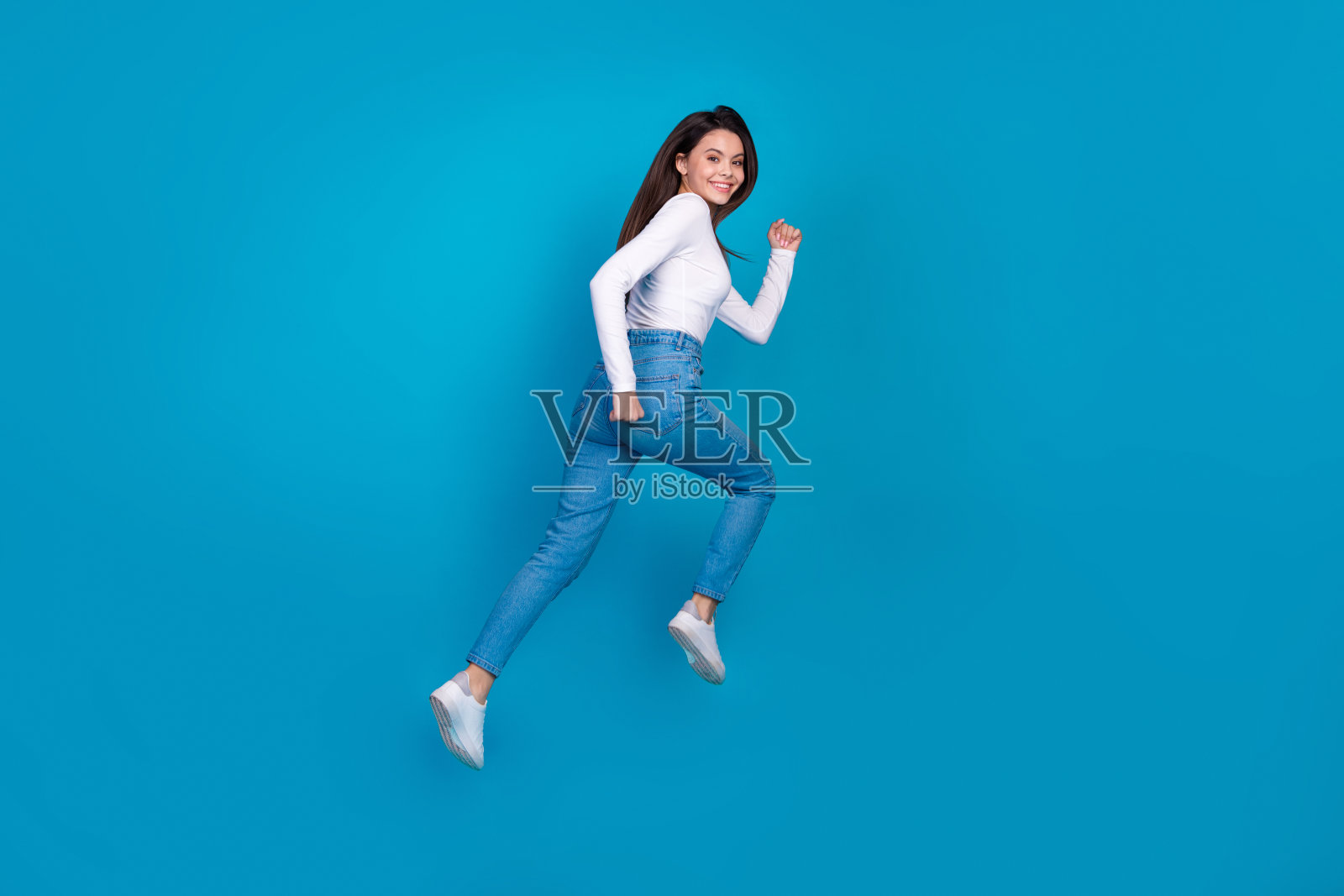 全身照片，漂亮的少女快速奔跑，背影穿着时尚的白色服装，背景为蓝色。照片摄影图片