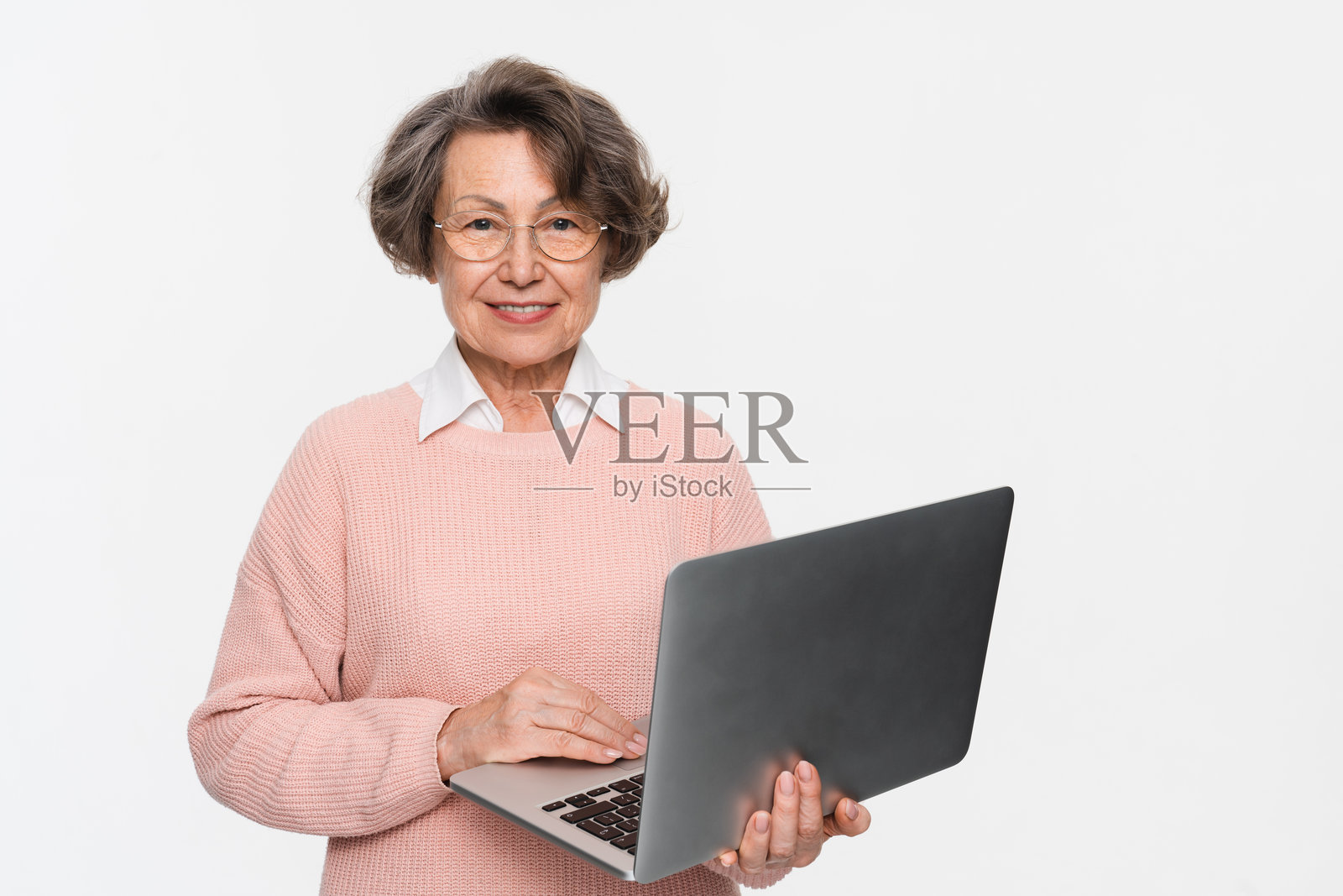 老年女性使用笔记本电脑，在线工作，与家人沟通。照片摄影图片