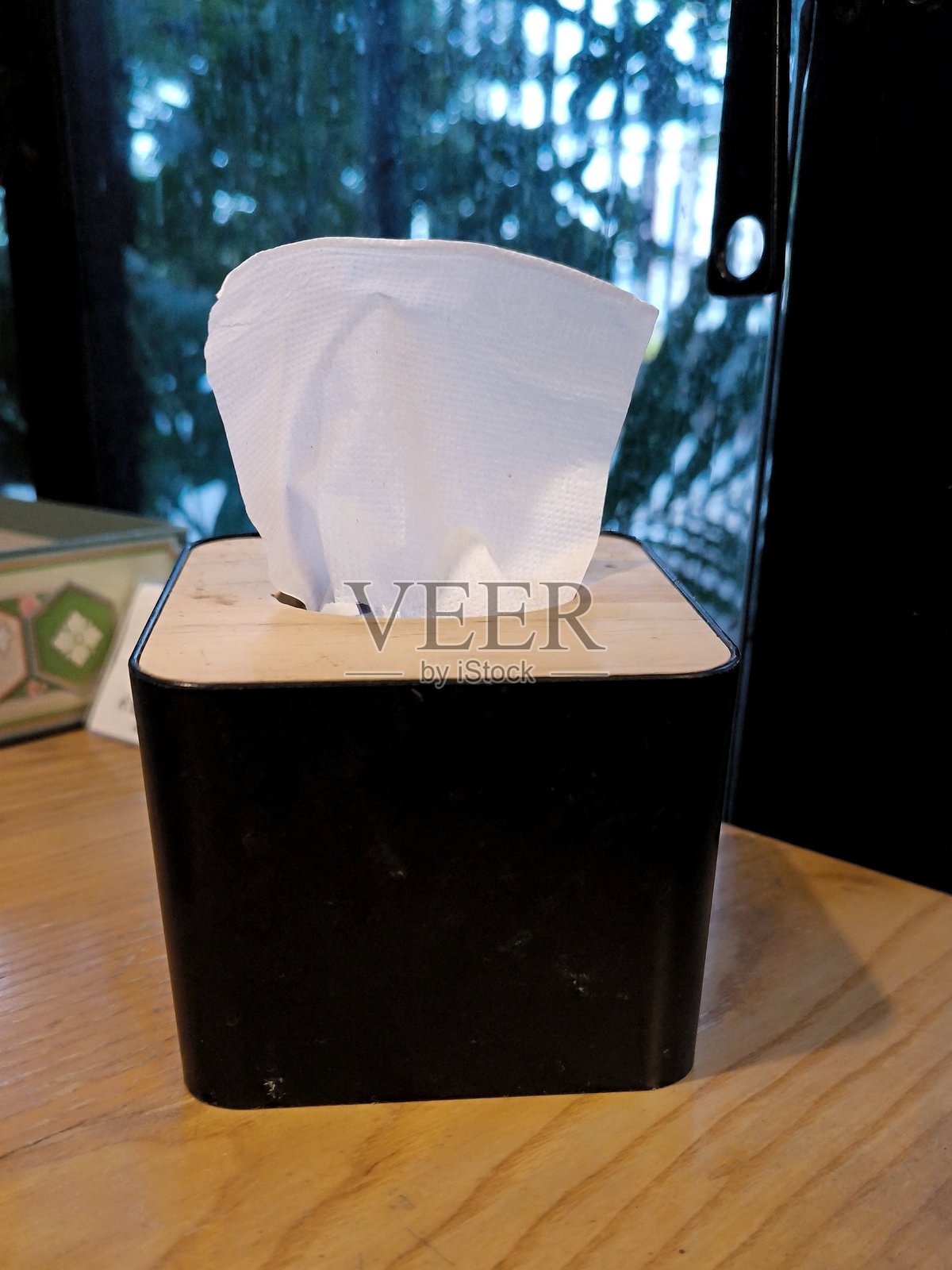 木桌上黑色纸巾盒里的餐巾纸。纸巾。照片摄影图片