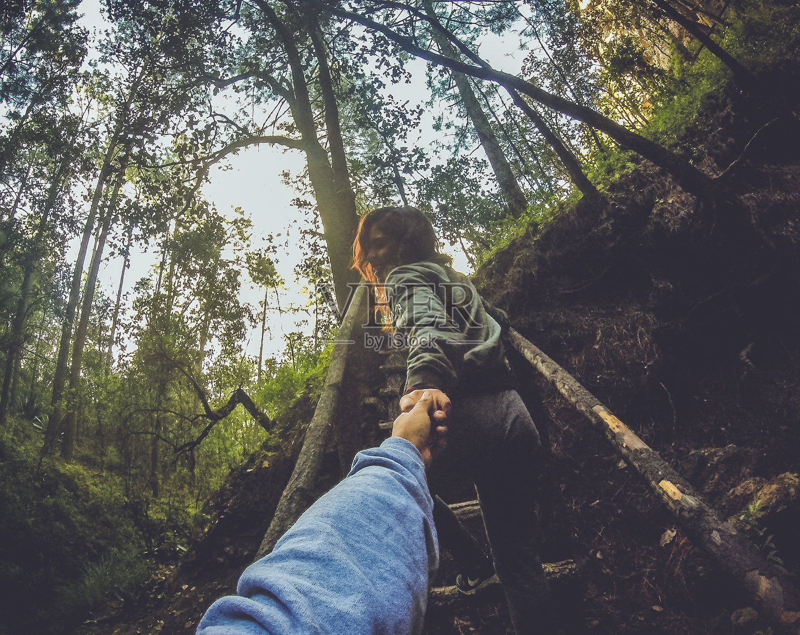 男朋友在森林中的木楼梯上牵着女朋友的手的特写图像照片摄影图片