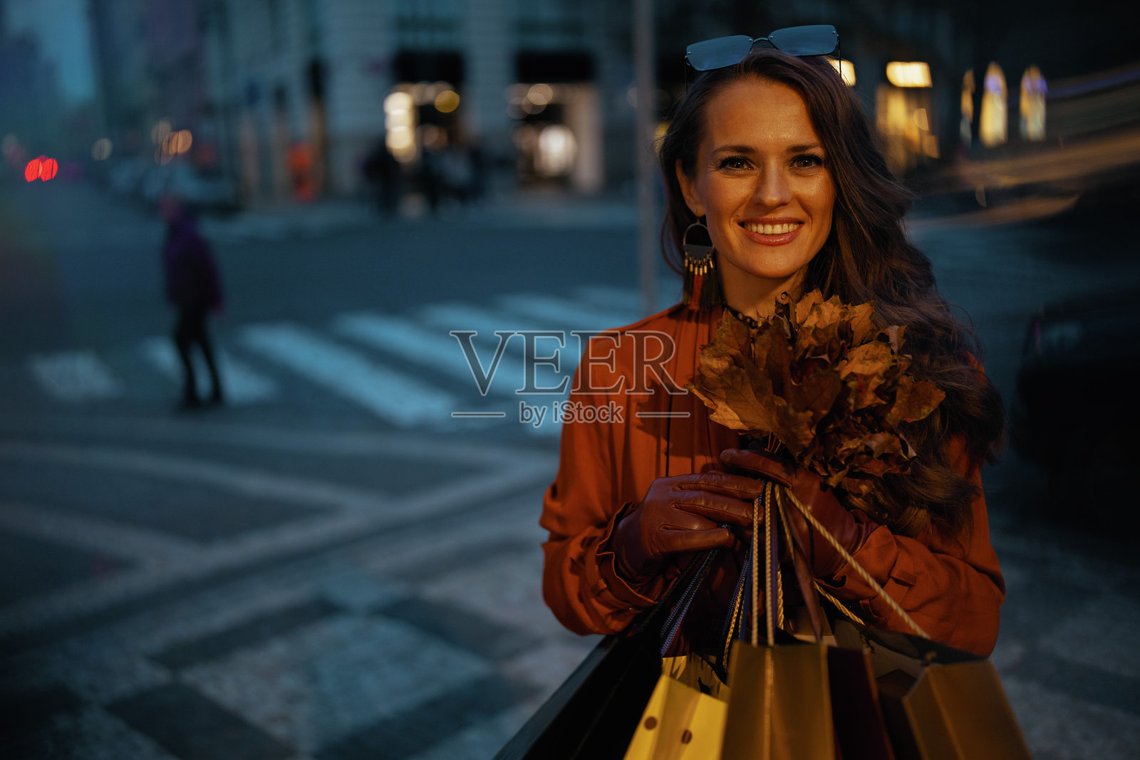 穿着棕色风衣挎着购物袋微笑的时髦女人照片摄影图片