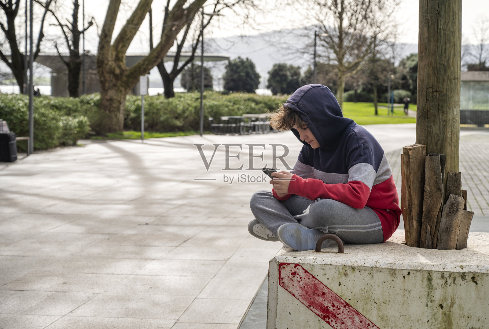 青少年坐在户外，专注于他的智能手机照片摄影图片