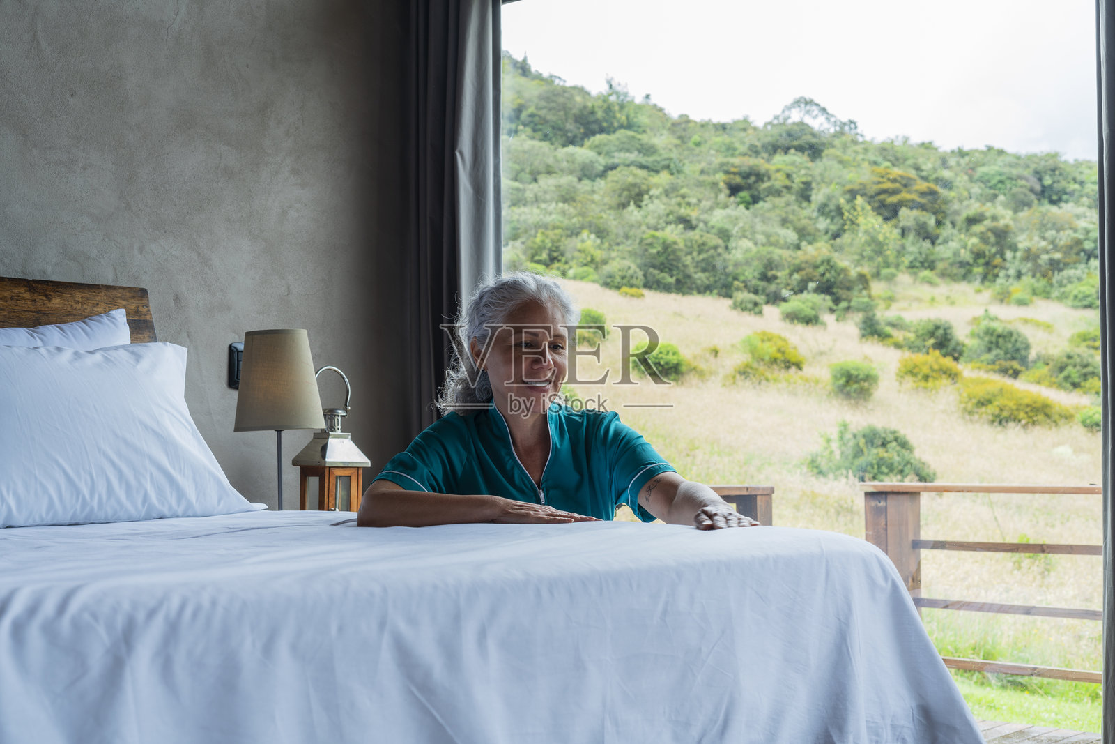 一个成年女性在酒店房间里整理床铺，微笑着享受她的工作照片摄影图片