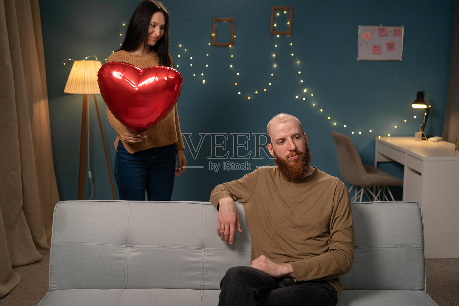 在家庆祝情人节。深爱的女人手持心形气球，想要给男朋友一个惊喜。照片摄影图片