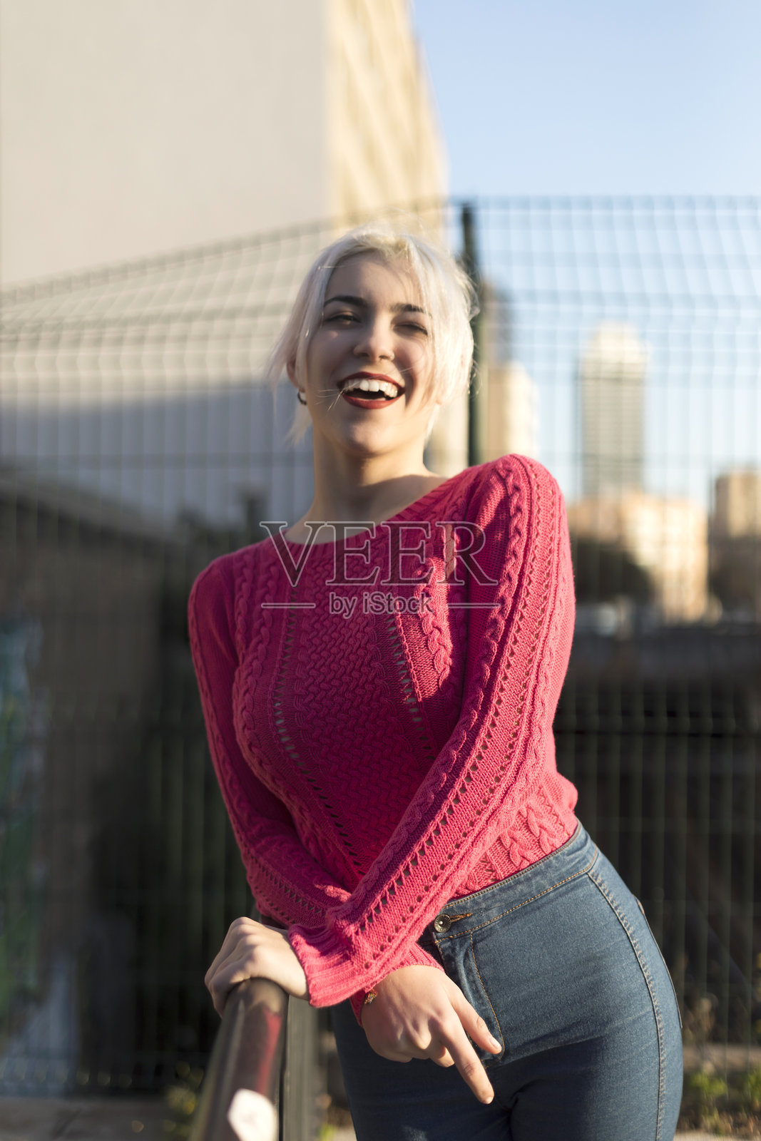 穿着红色毛衣的年轻女性在户外微笑照片摄影图片