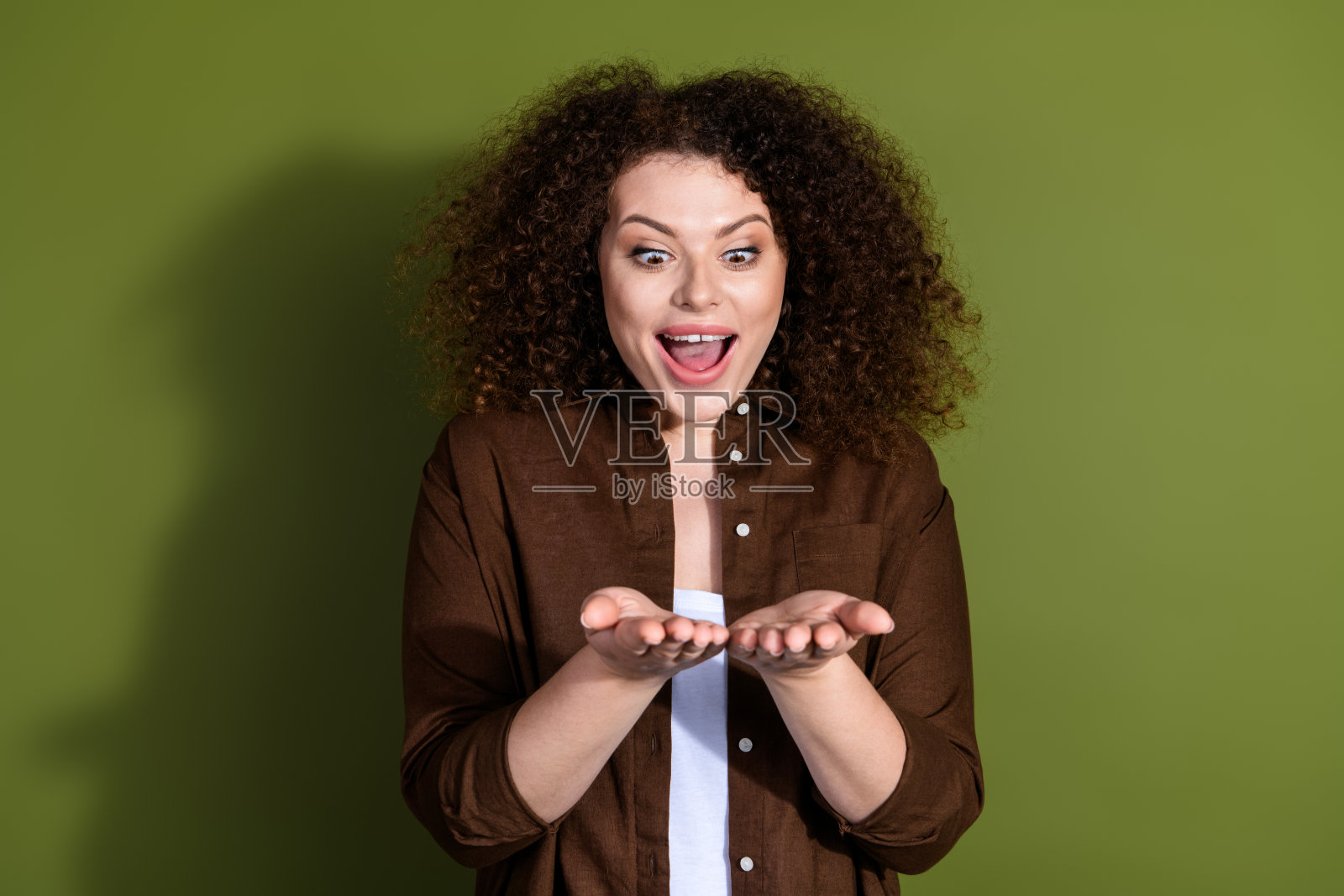 穿着棕色衬衫的漂亮年轻女孩在卡其色背景上摆出空白空间的姿势照片摄影图片