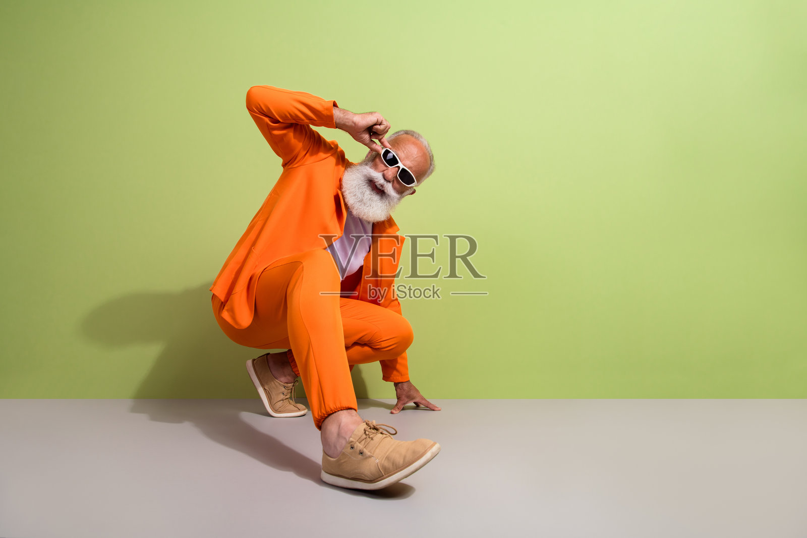 穿着橙色西装、空旷空间鞋子的搞笑奢华男士全身照，背景为绿色。照片摄影图片