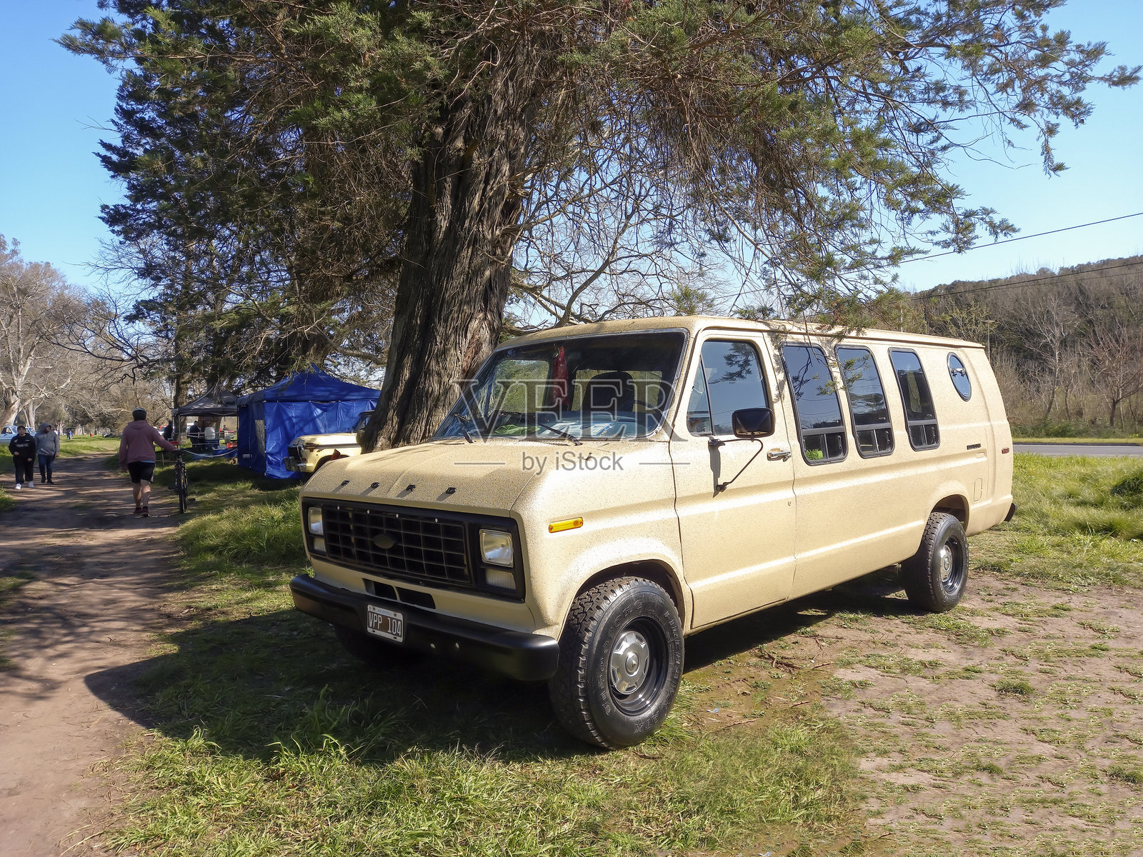 1983年老式奶油色福特Econoline E 150露营车，停在公园的草地上，参加经典汽车展。照片摄影图片