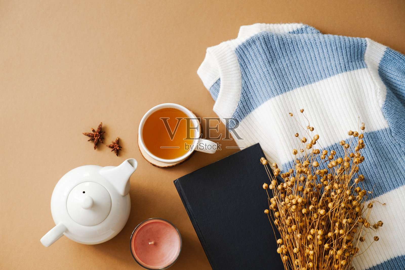 舒适的平铺画面，包含条纹毛衣、茶、书籍、干花和蜡烛，背景为米色。非常适合生活方式博客、家居装饰和秋季主题。照片摄影图片