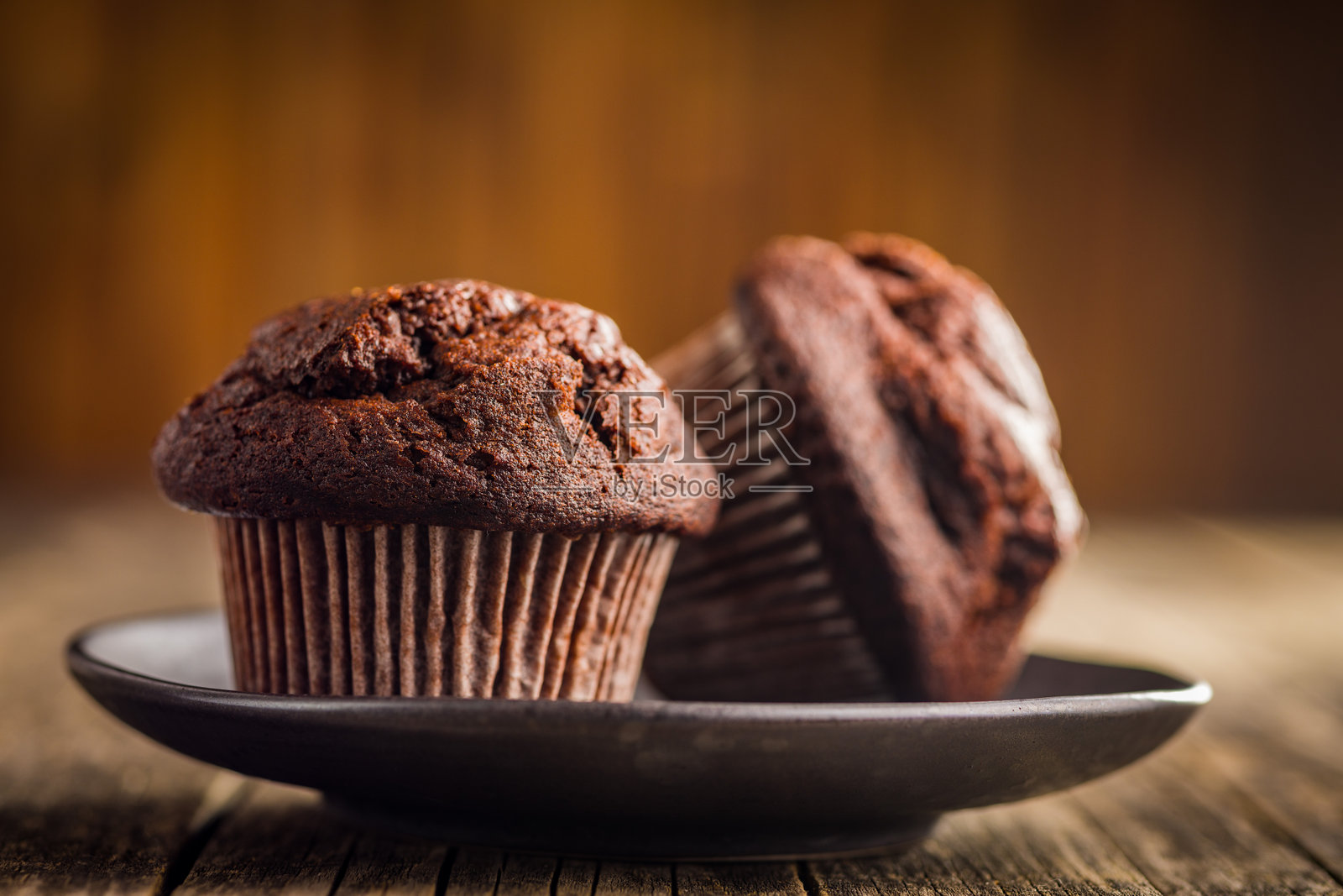 甜美的巧克力松饼蛋糕放在木桌上的盘子里。照片摄影图片