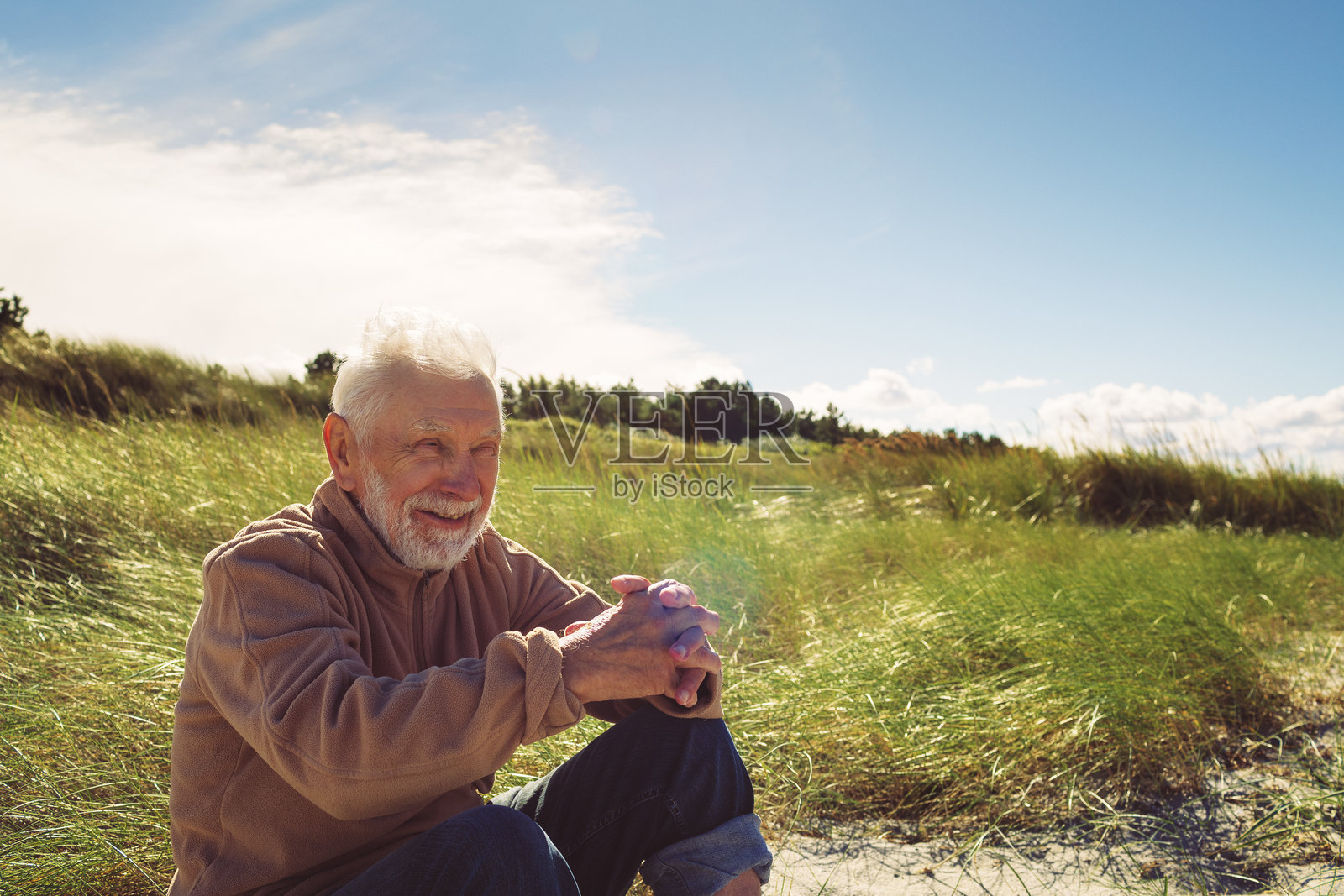友好的老人在海滩上坐着，享受着海边的阳光。照片摄影图片