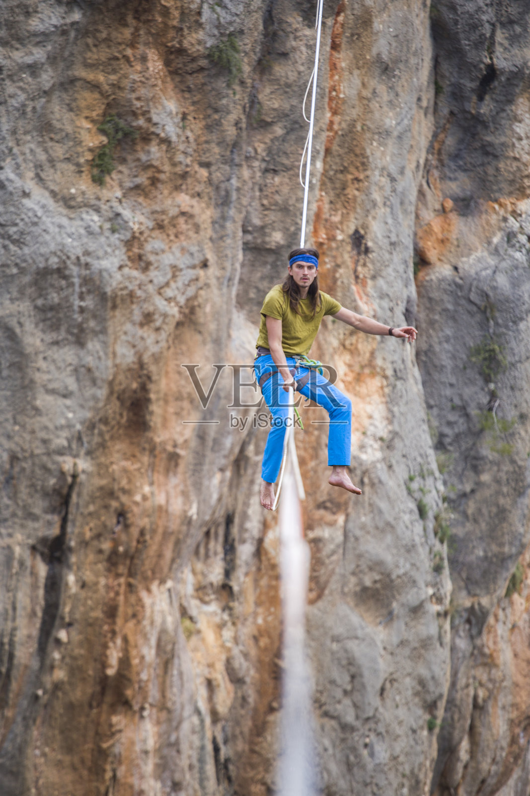 走钢丝的人在悬崖上方的绳索上行走。照片摄影图片