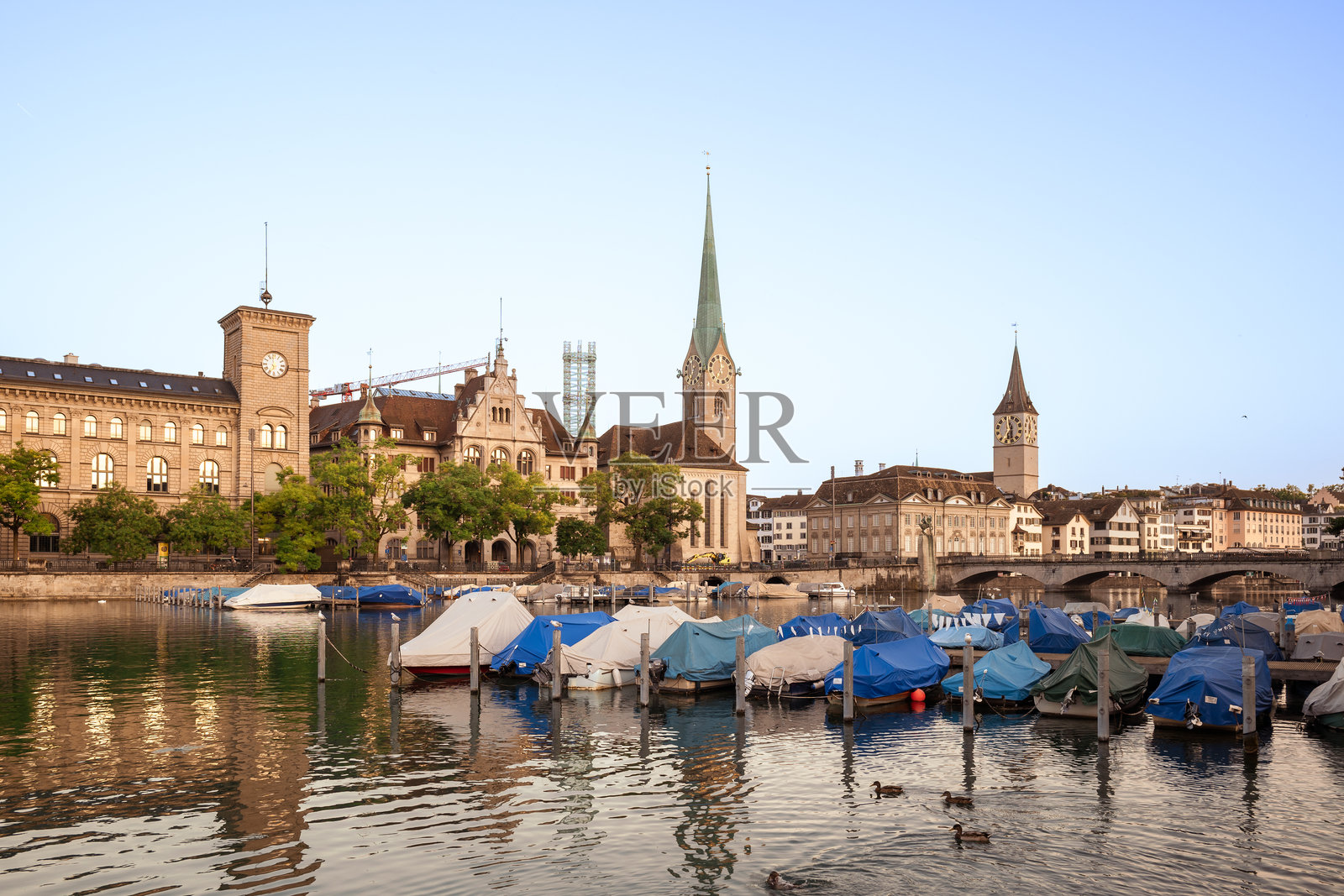 2024年3月9日，瑞士苏黎世。日出时分的旅游老城区。夏季黎明，沿利马特河长廊著名的教堂，戏剧性的云彩和水面倒影。照片摄影图片