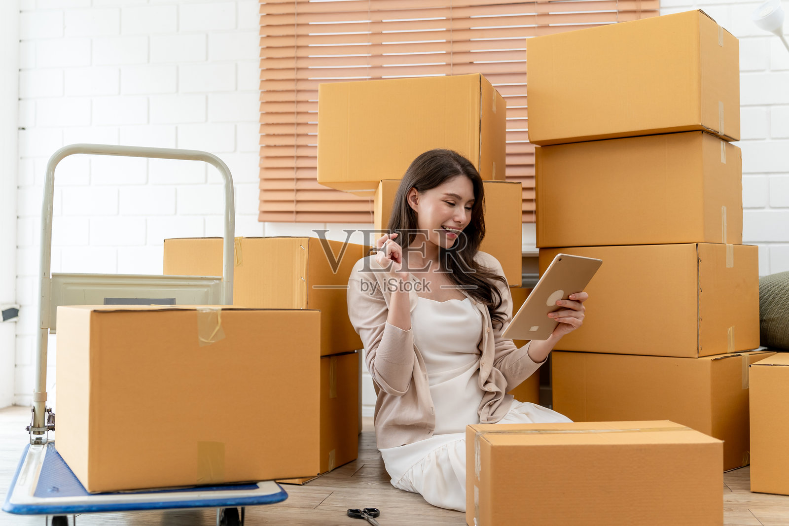 亚洲年轻女性在搬家时收集带有回忆的物品。迷人的美丽女孩高兴地手持箱子和行李，置身于新家。搬家和迁移的概念。照片摄影图片