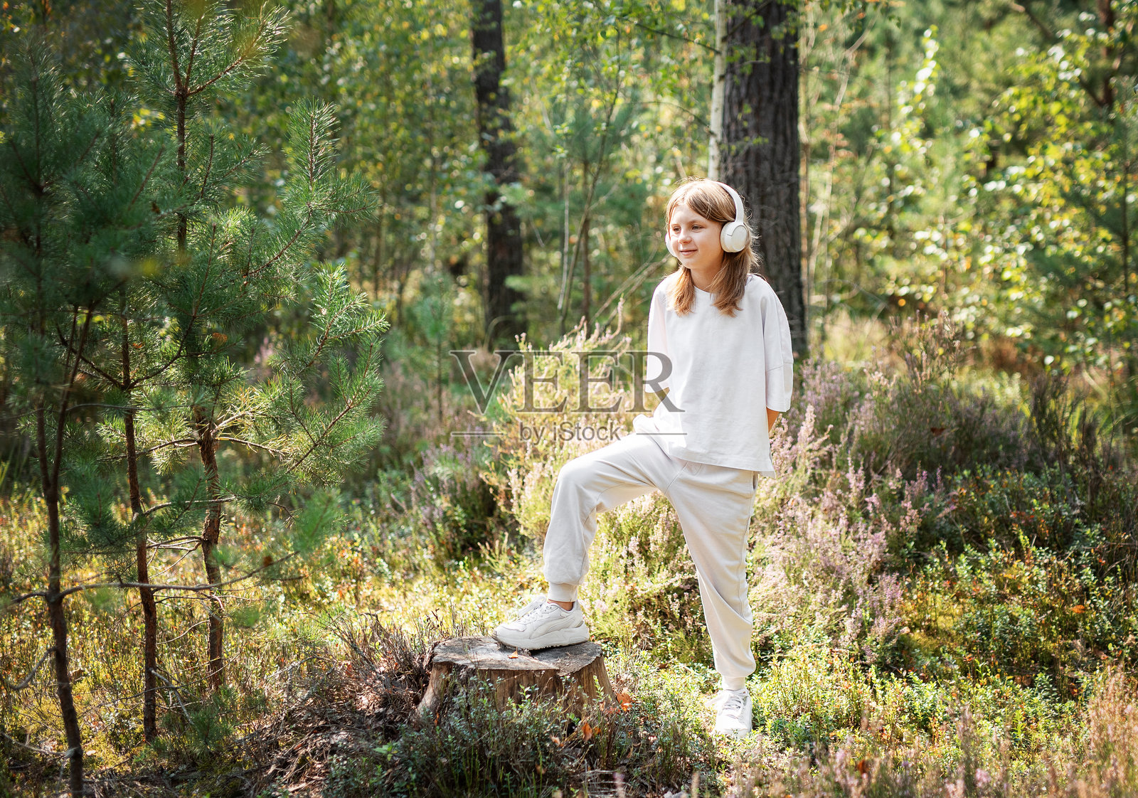 女孩戴着耳机听音乐。照片摄影图片