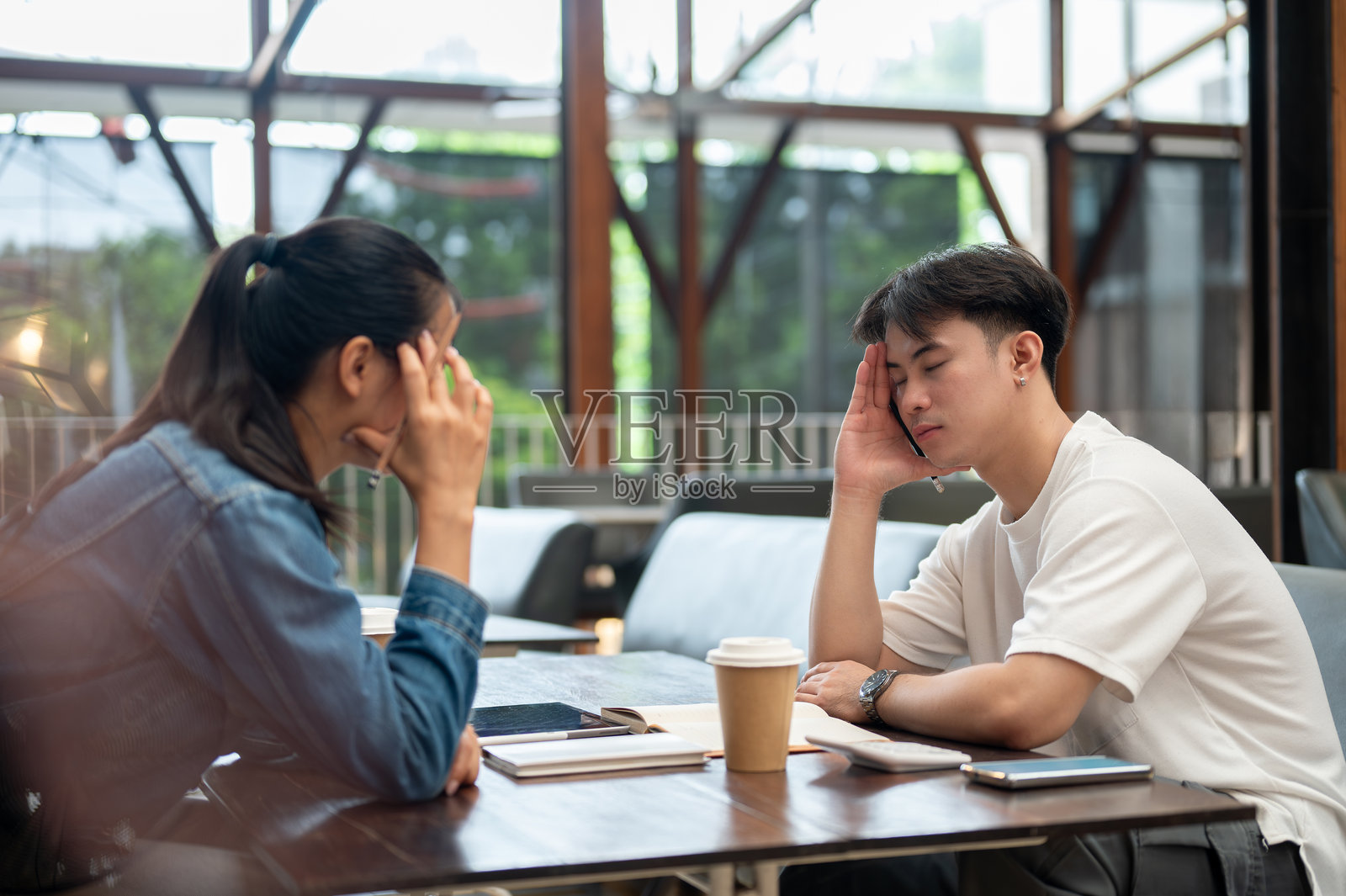 一位严肃、紧张的亚洲男性正在倾听同事讨论与工作相关的问题。照片摄影图片