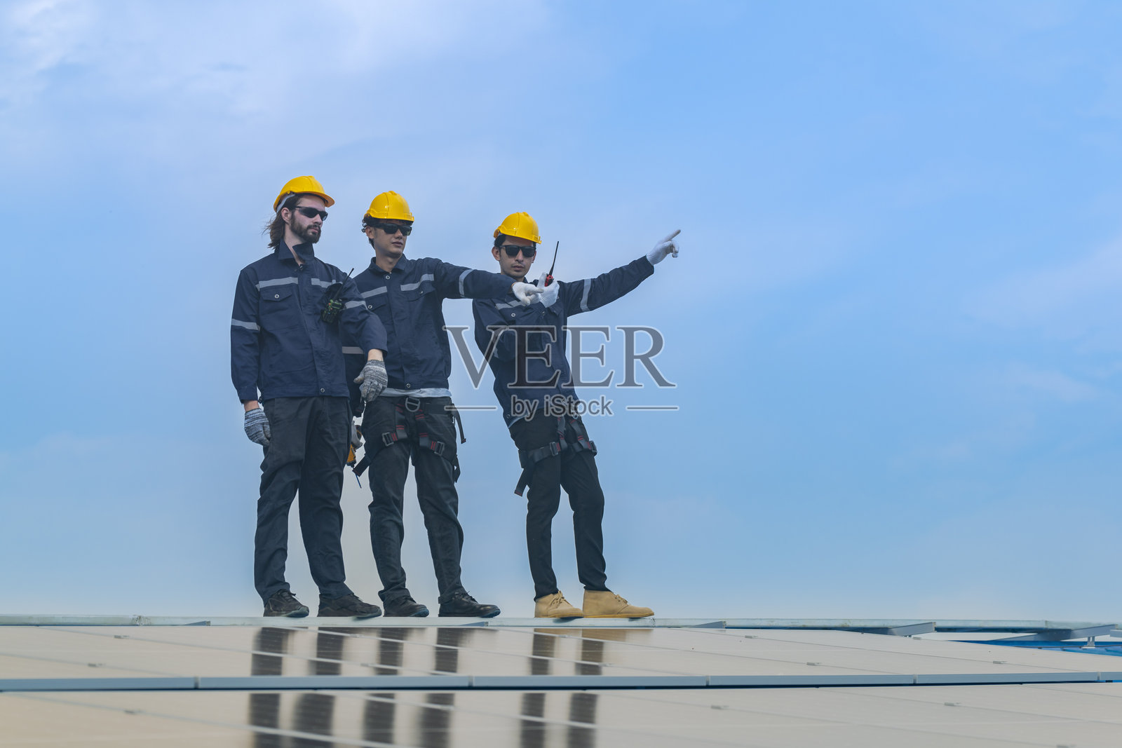 工人技术人员正在屋顶上安装太阳能光伏板系统。男性技术人员在屋顶结构上行走，以检查光伏太阳能模块。照片摄影图片