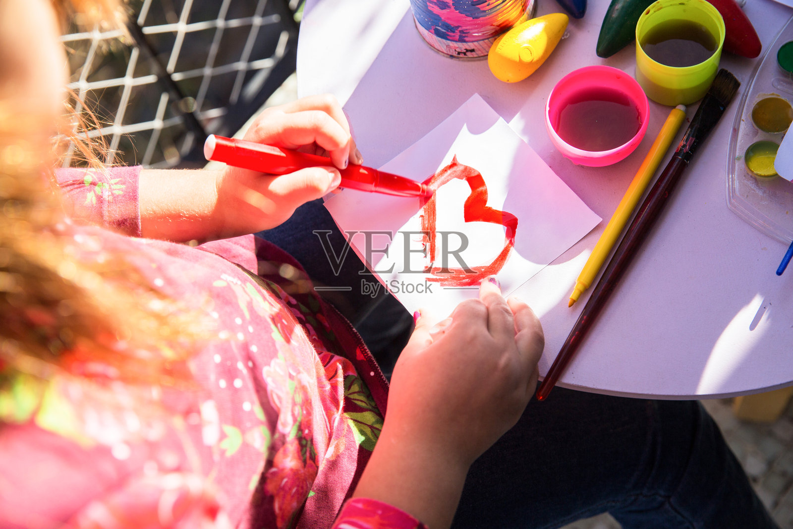 一个孩子在阳光明媚的下午用马克笔和颜料创作五彩缤纷的艺术作品照片摄影图片