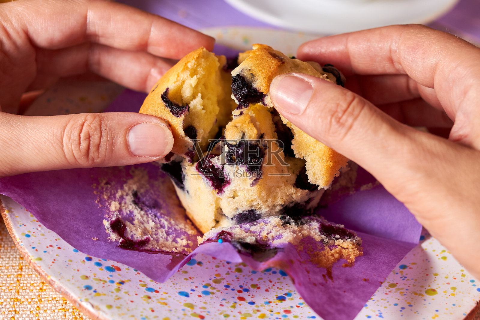 女人的手展开了一只新鲜制作的蓝莓杯子蛋糕。新鲜自制的甜蜜在女人的手中。照片摄影图片