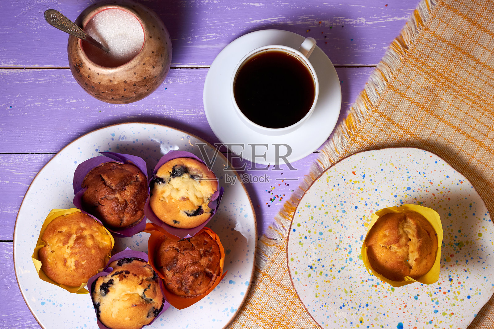 从上方俯视紫色桌面上的甜美松饼、杯子蛋糕和一杯咖啡照片摄影图片