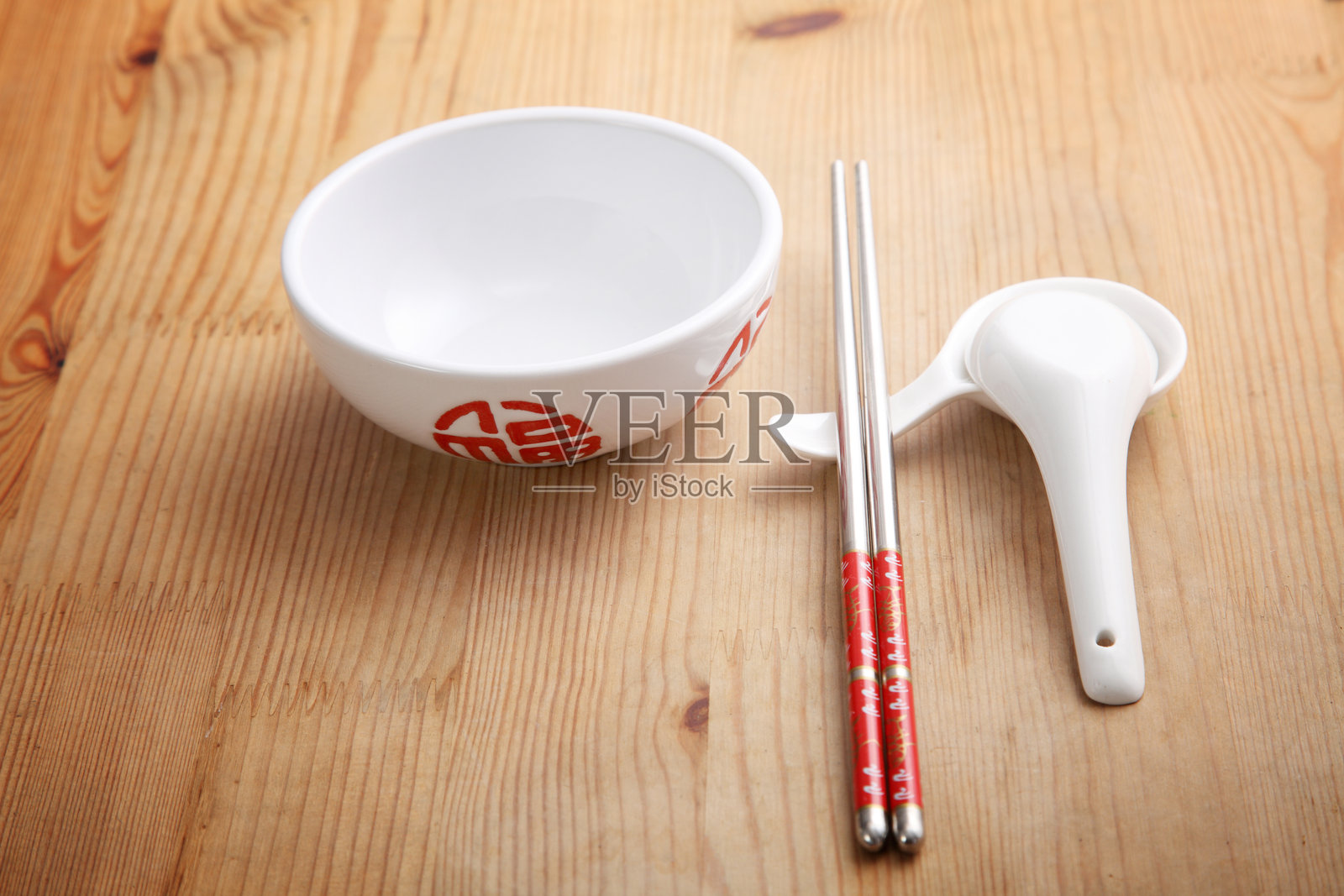 高角度视图的筷子放在碗旁的勺子上，桌子上。照片摄影图片