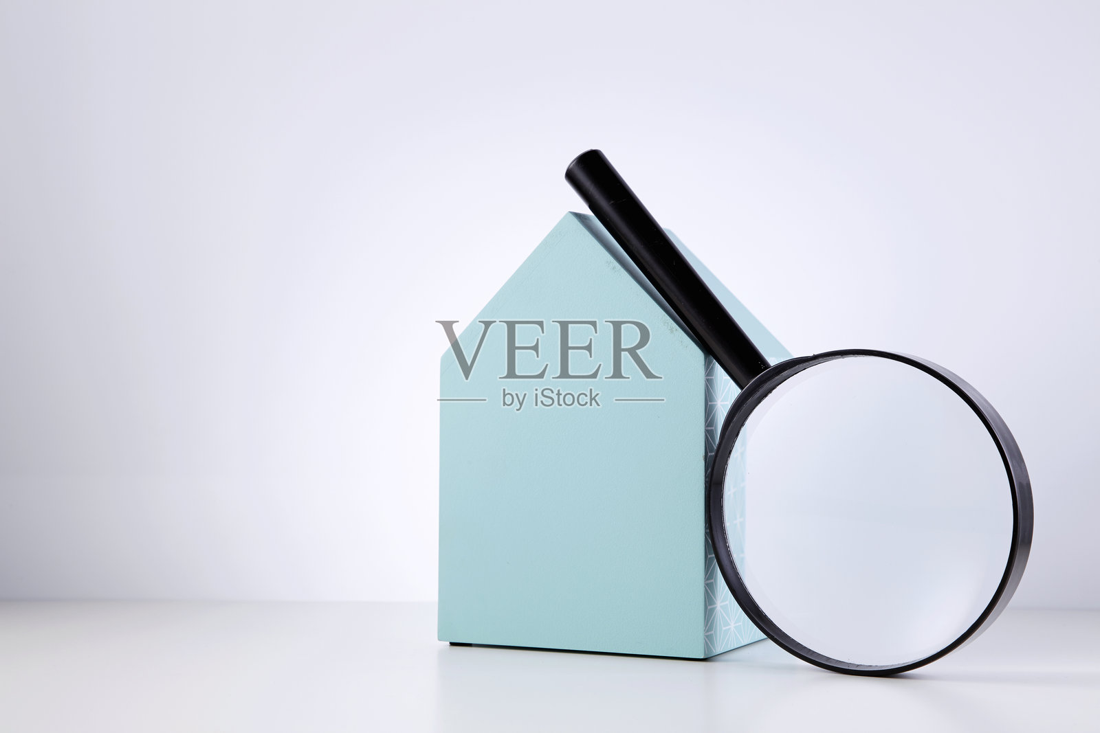 放大镜和模型房屋的特写，背景为白色桌面照片摄影图片