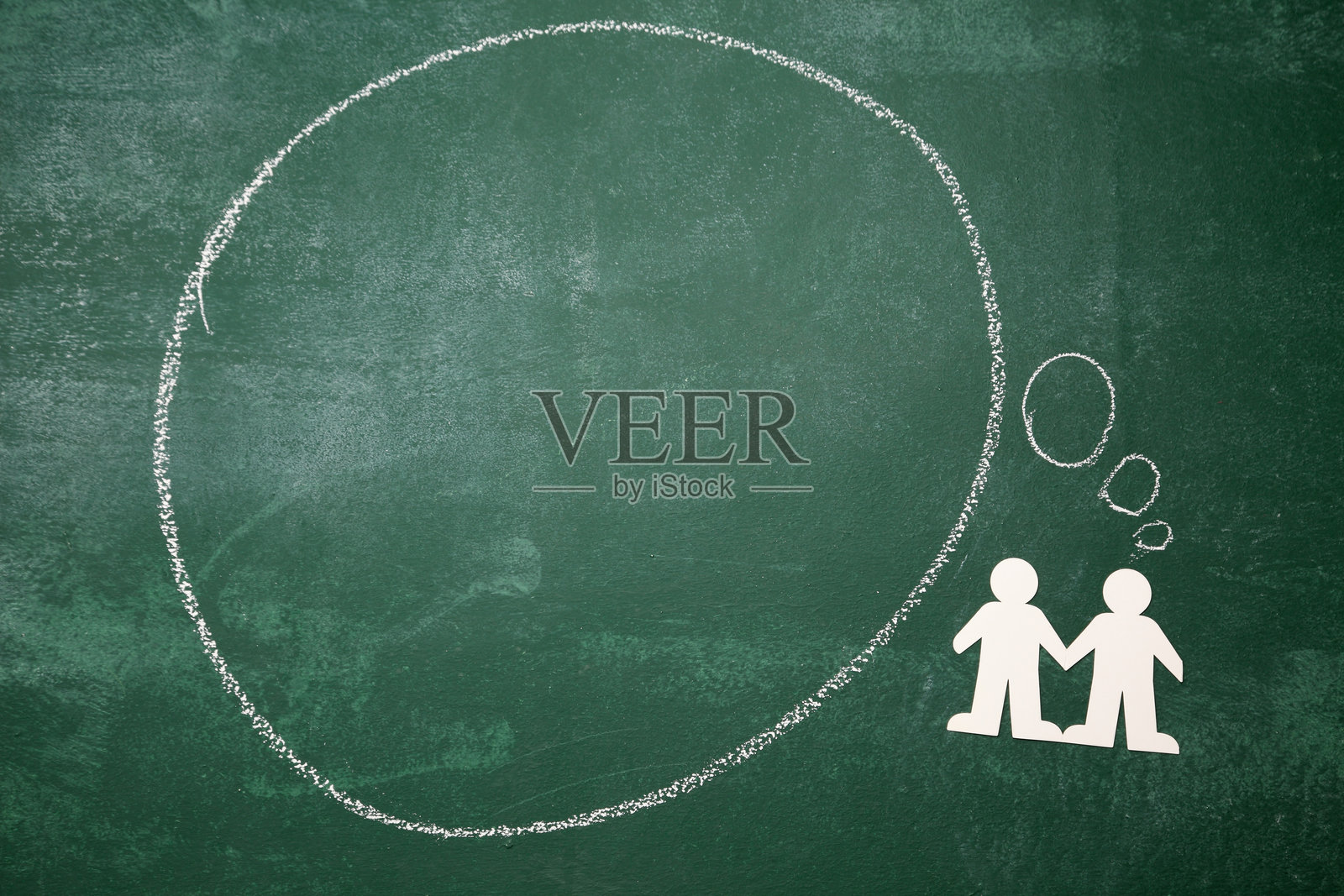 黑板上空白对话气泡的正上方拍摄，旁边有纸链照片摄影图片