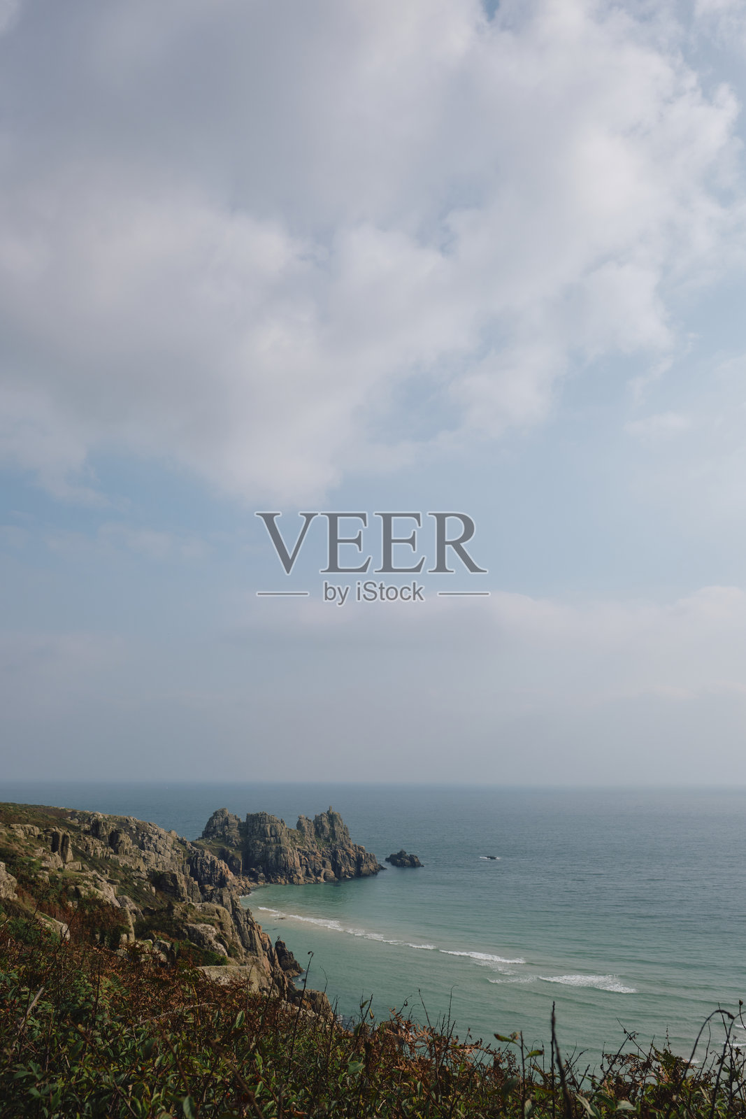 在阳光明媚、雾气弥漫的九月下午，俯瞰康沃尔的佩登·冯德海滩和洛根岩的海景。照片摄影图片