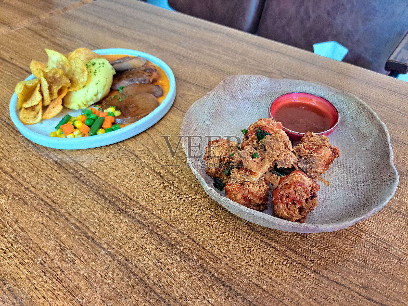 美味的迷你炸鸡腿配辣酱，盛在碗中。舌尖牛排配土豆泥、薯片、烤牛舌、牛排酱和混合蔬菜。菜单。照片摄影图片