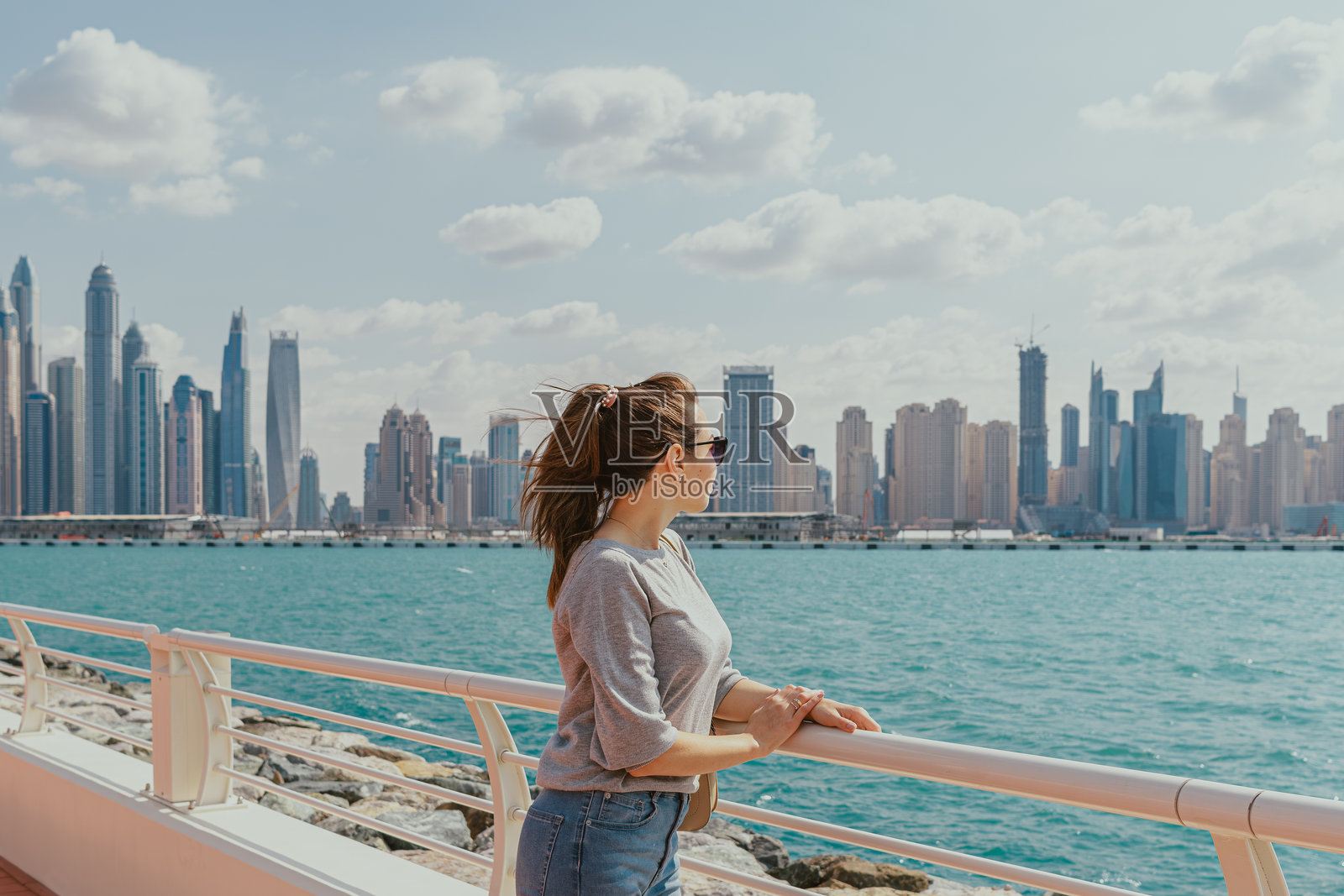 女人在海滨走道上俯瞰城市天际线照片摄影图片