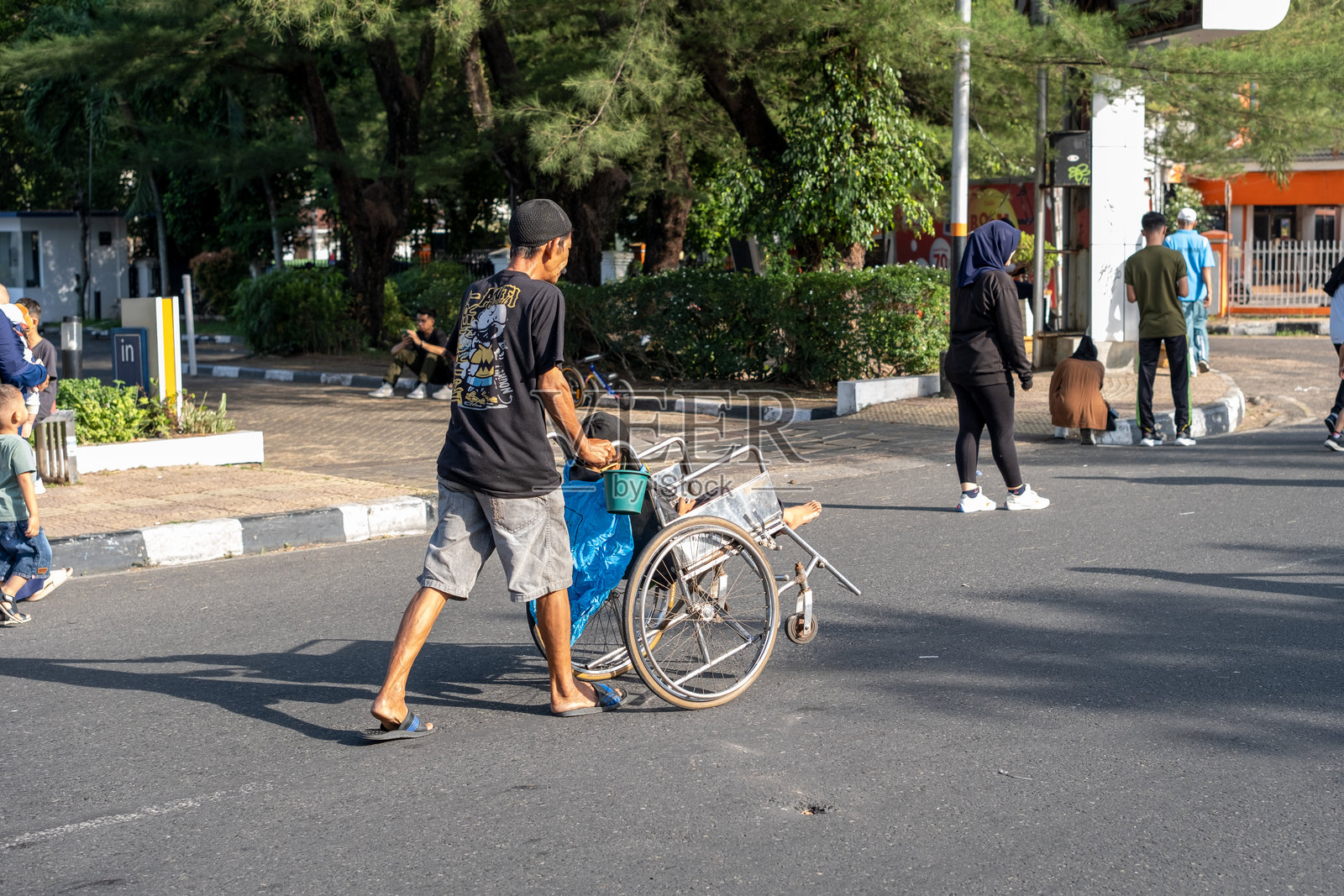 一名男子正在推着一位坐在轮椅上的人穿过街道照片摄影图片