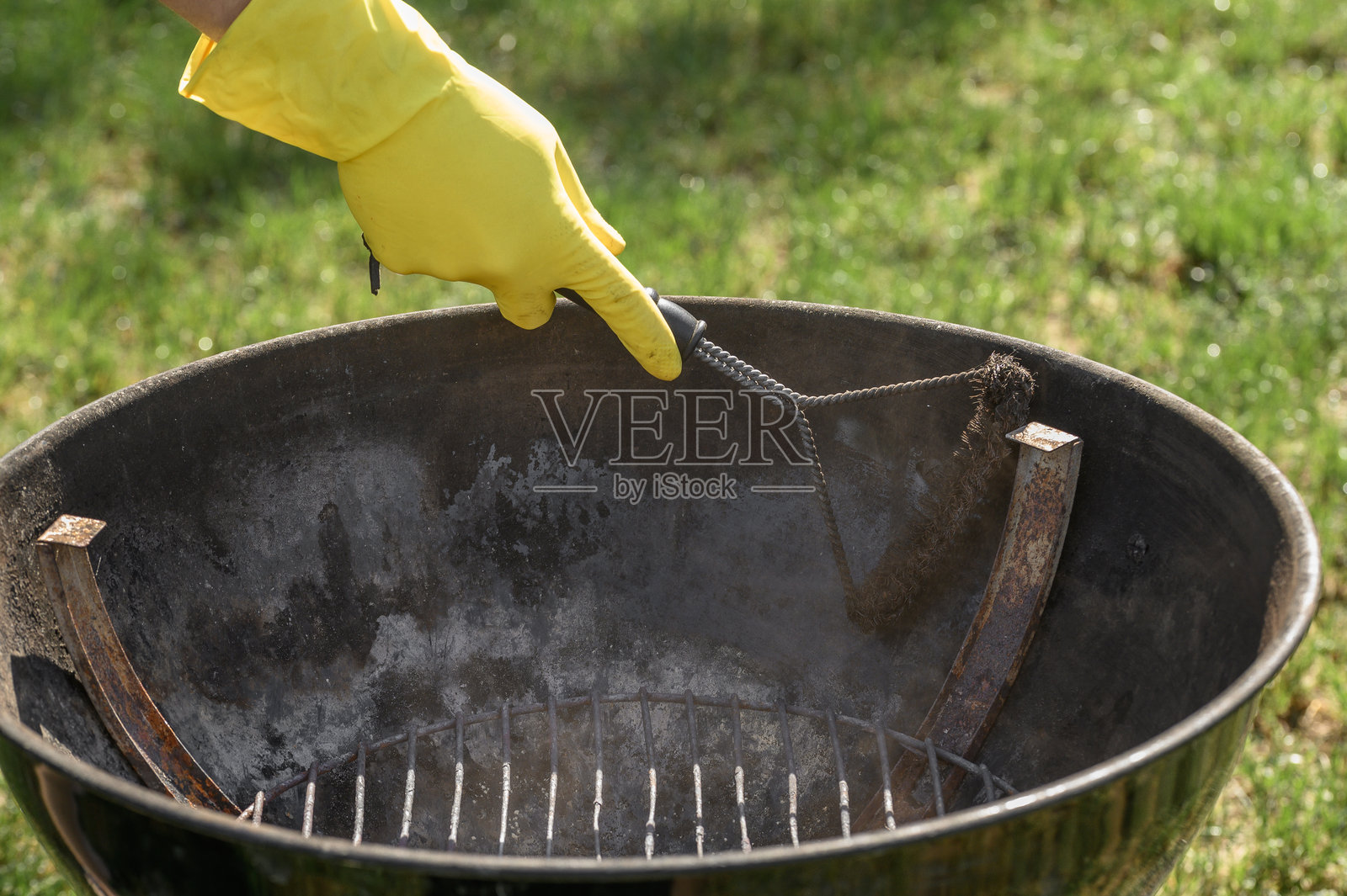 清理花园烧烤炉中的金属火箱，去除燃烧油脂和木炭残留物后形成的旧沉积物照片摄影图片