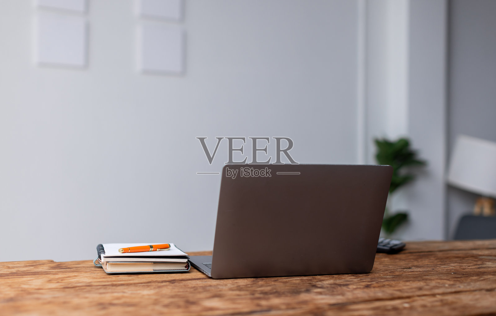 在下班后，笔记本电脑、笔记本和眼镜放在大型开放式办公室的桌子上。照片摄影图片