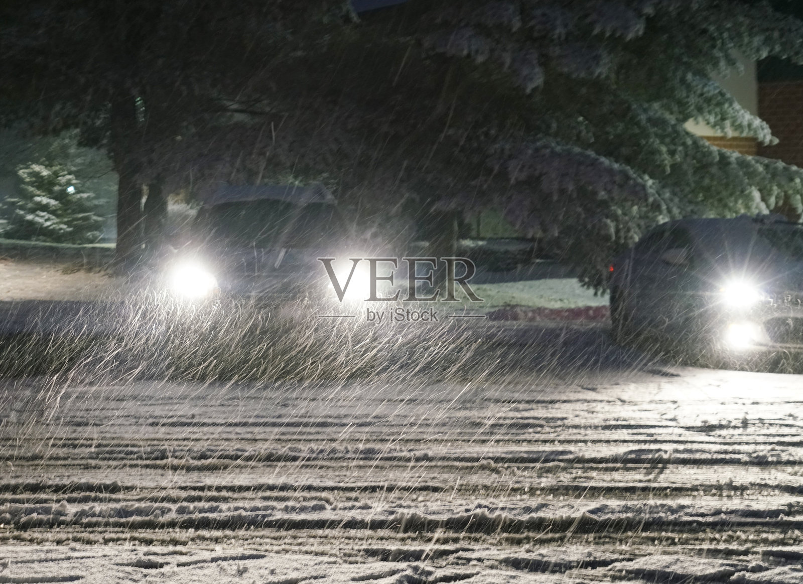 夜间暴风雪中的汽车前灯上的雪照片摄影图片