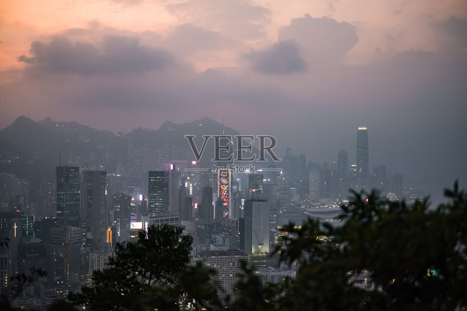 香港岛粉色日落天际线景观，前景有云和树木照片摄影图片