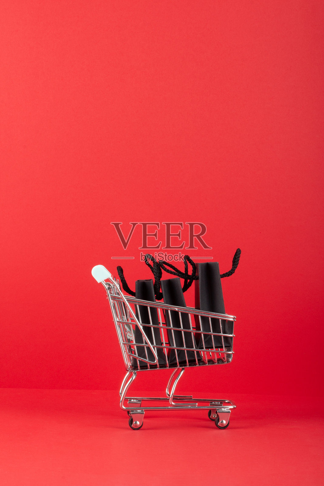 红色背景上的购物车与黑色购物袋。垂直横幅。购物概念。照片摄影图片